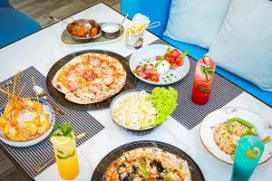 Table spread of pizza, salad and drinks at Bilkana Rooftop